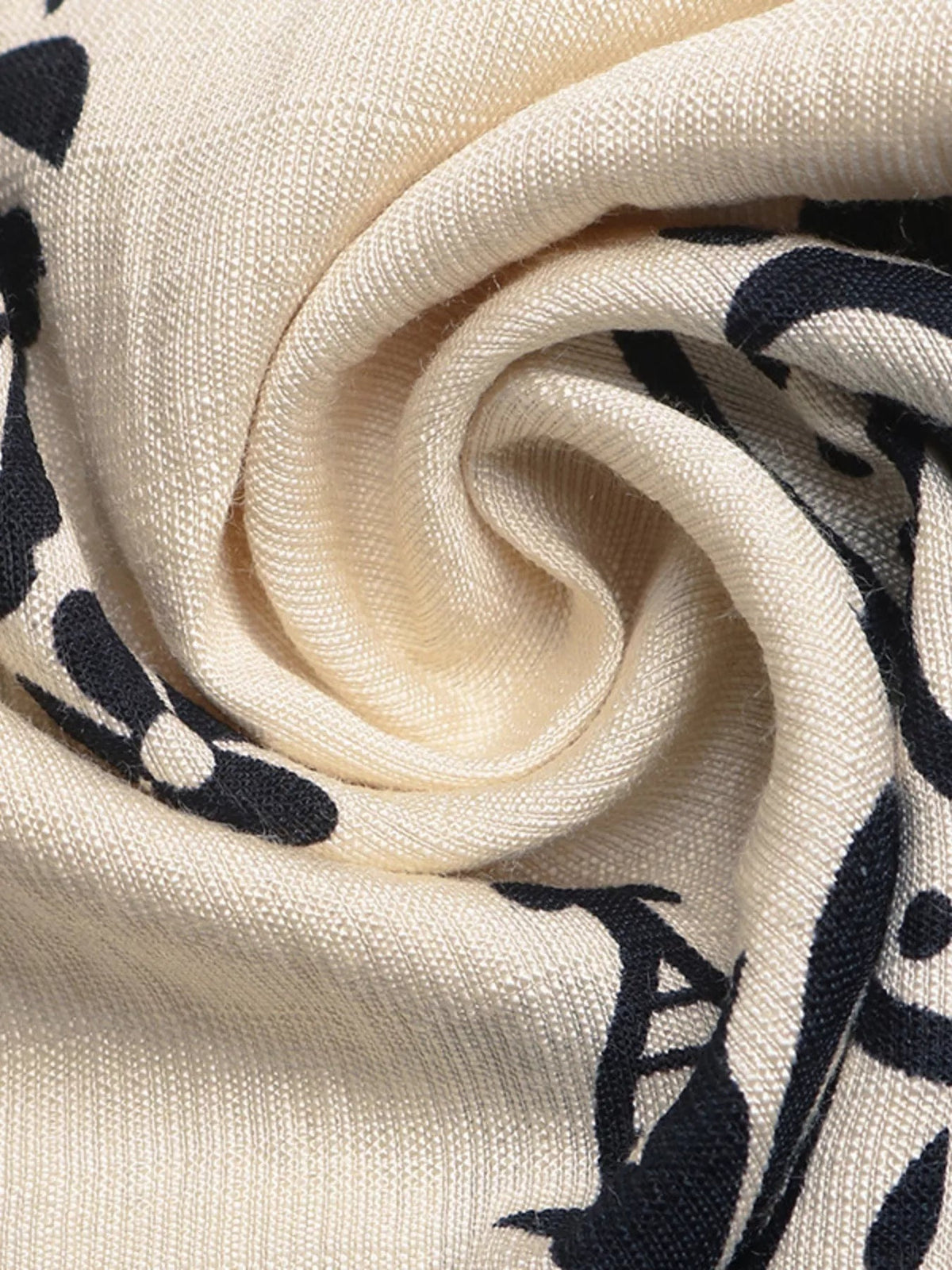 Close-up of beige boho print wide-leg pants showing black abstract motifs, soft draping, and a lightweight woven fabric texture.