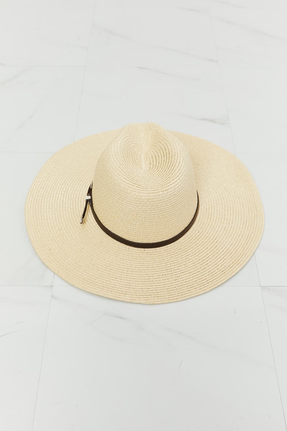 Ivory boho straw fedora with a softly structured crown, wide woven brim, and contrasting dark band accented by a small metallic buckle.