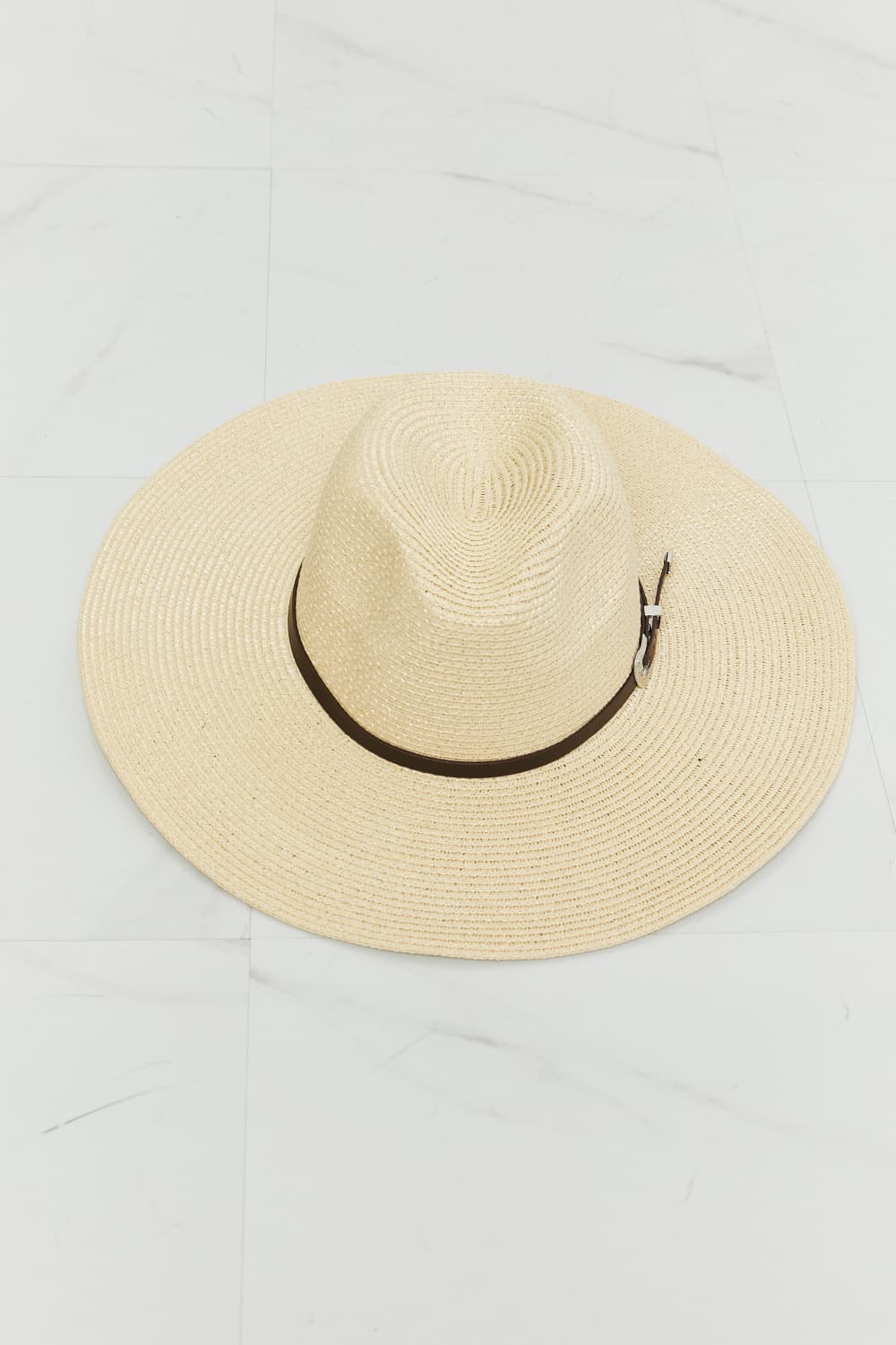 Ivory woven straw fedora with a softly structured crown, wide brim, contrasting dark band, and small metallic buckle detail.