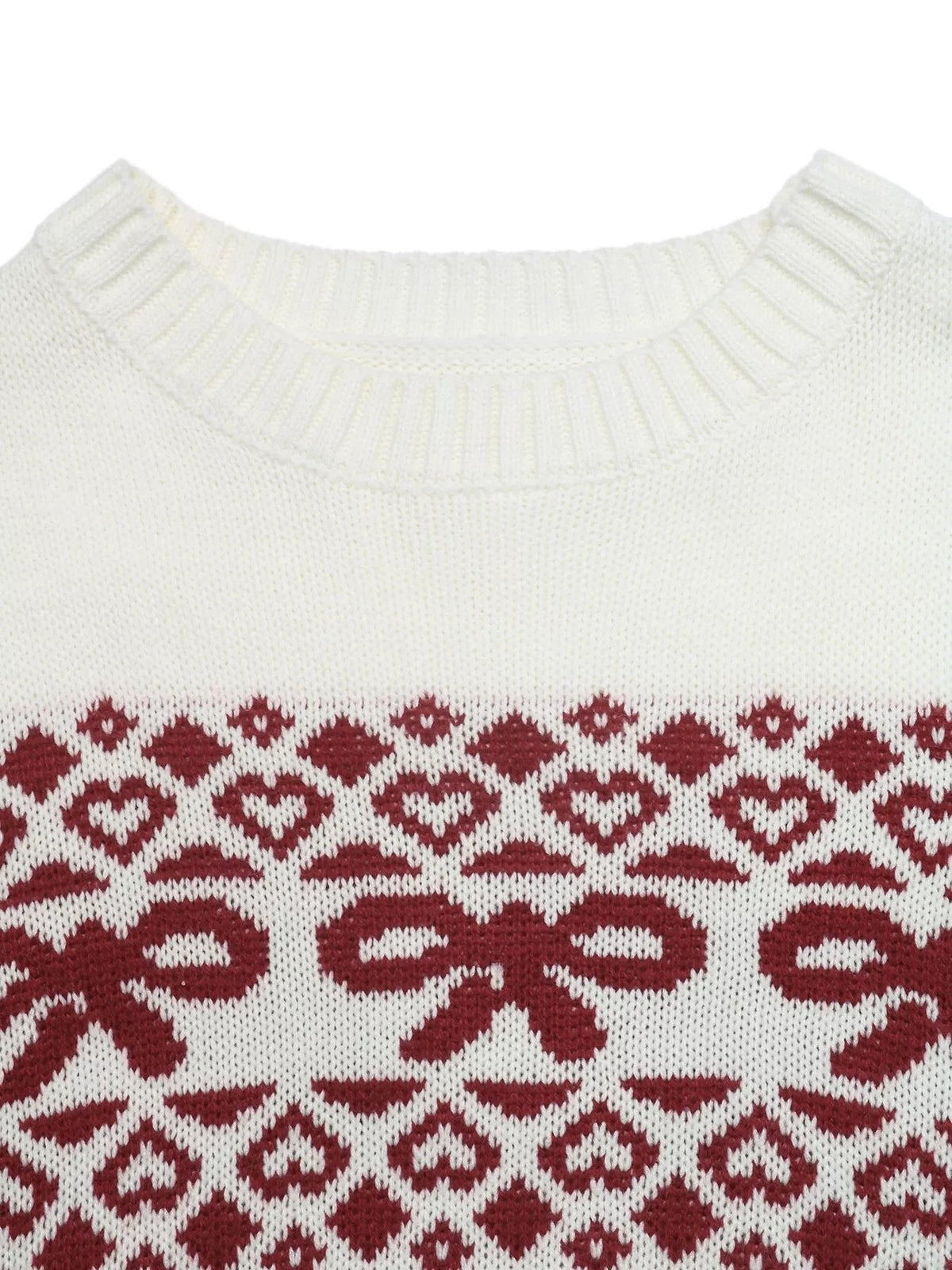 White knit Christmas sweater close-up showing a ribbed crew neckline and burgundy holiday pattern with bows, hearts, diamonds, and geometric motifs.