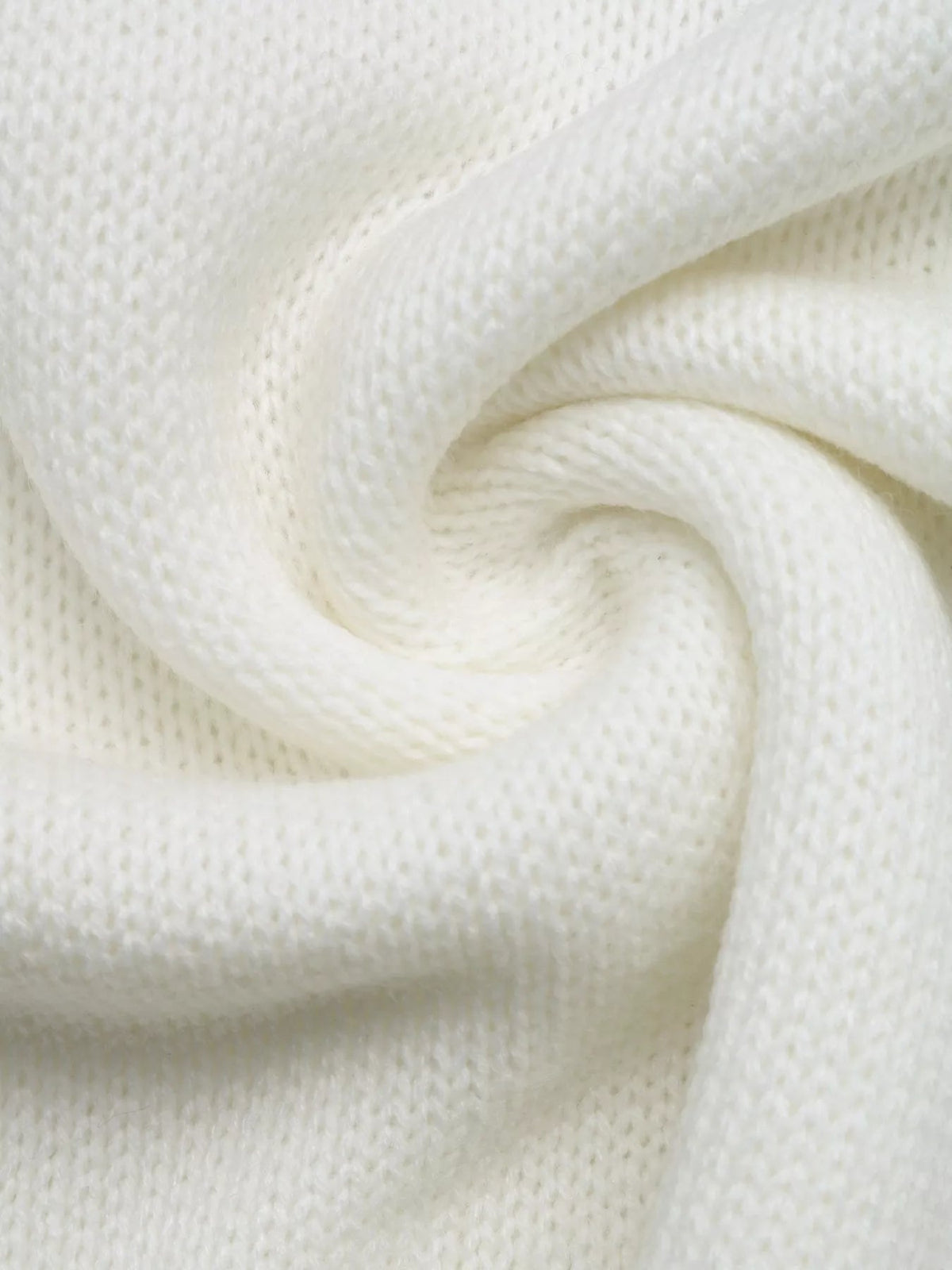 Close-up of a soft ivory acrylic knit sweater showing its textured construction and folded fabric.