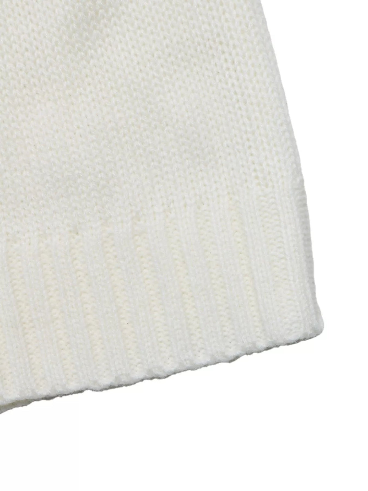 Close-up of the ivory acrylic Christmas sweater showing its soft textured knit construction and gently finished curved edge.