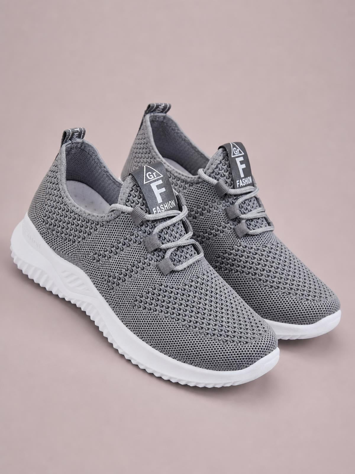 Gray breathable mesh athletic sneakers with textured knit uppers, lace-up fronts, padded collars, and thick white rubber flat soles.