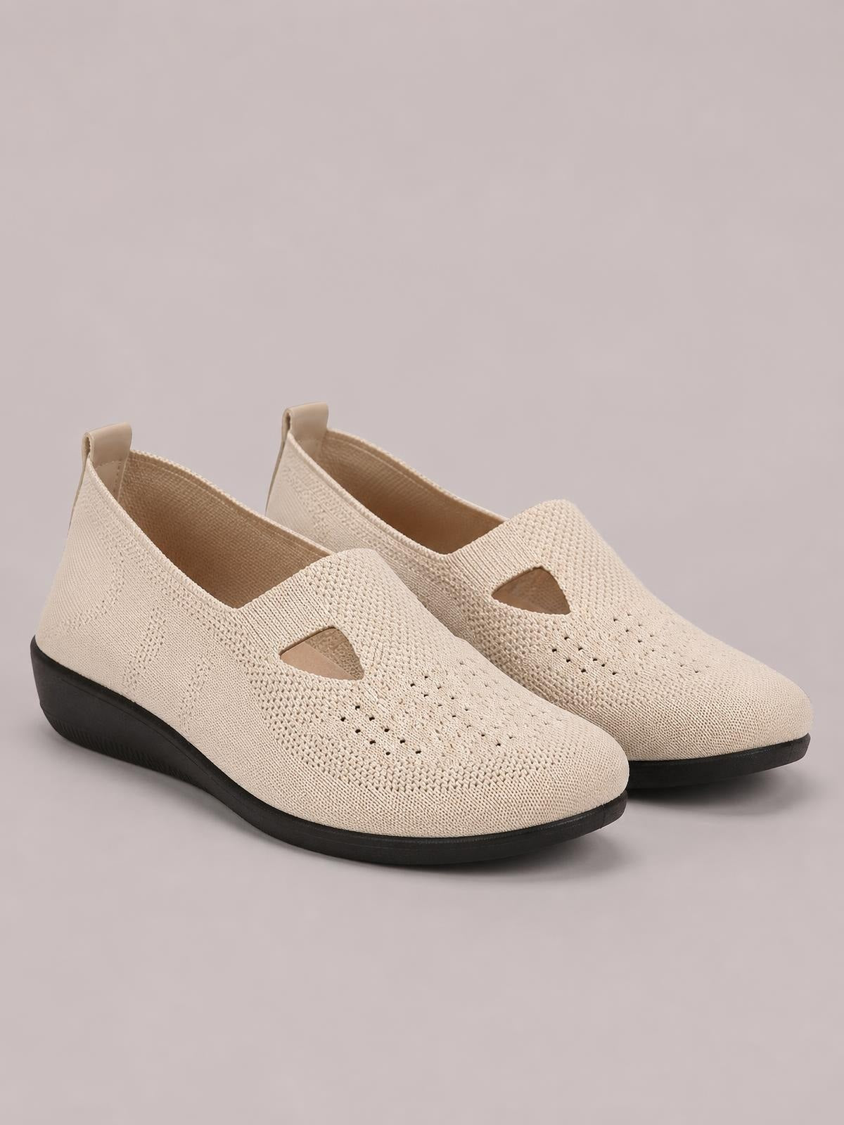 Beige breathable mesh round-toe flat slip-ons feature a perforated knit upper, easy slip-on design, and contrasting black rubber soles.
