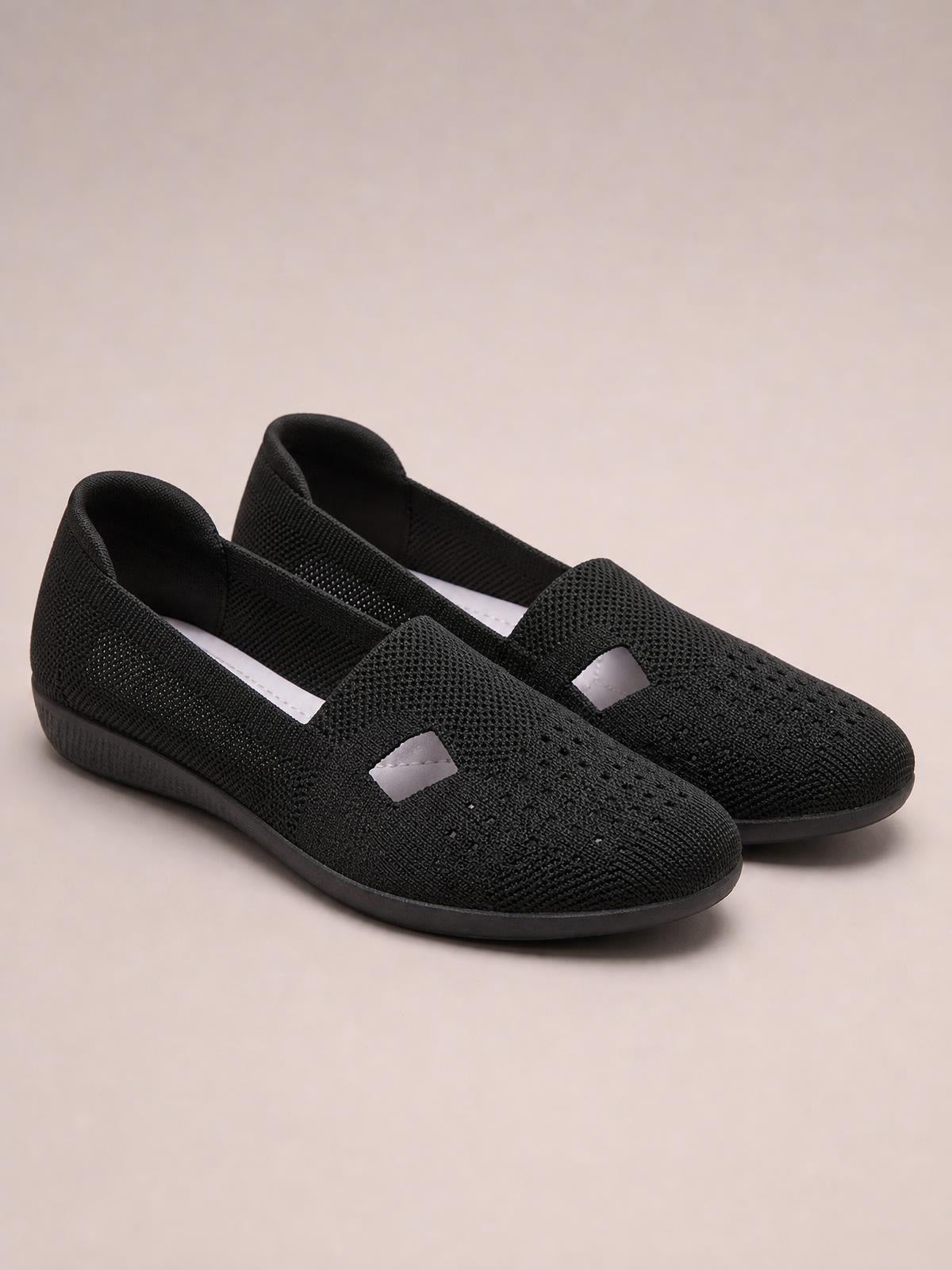 Black breathable mesh round-toe flat slip-ons feature a textured woven upper, open side cutouts, and flexible rubber soles.