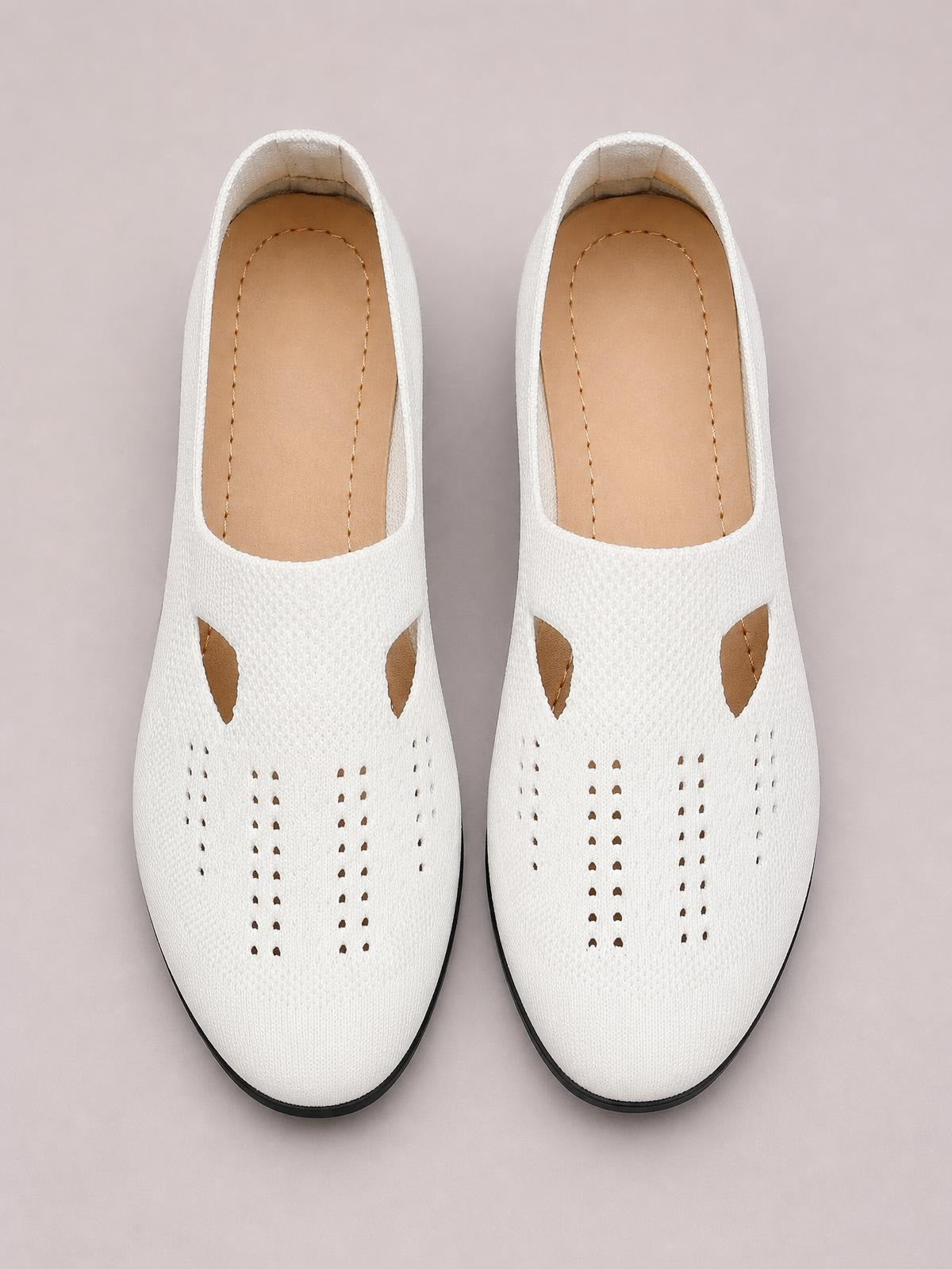 Pair of white breathable mesh round toe flat slip-ons with perforated uppers, tan insoles, and slim black rubber soles.