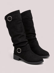 Black suede buckle accent slouch boots feature relaxed ruched shafts, wraparound straps with silver buckles, rounded toes, mid heels, and rubber soles.