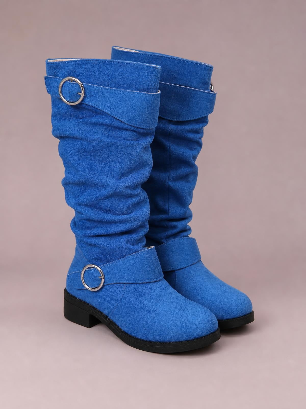 Bright blue suede slouch boots feature gathered shafts, wraparound buckle accents, rounded toes, and sturdy black rubber soles with mid heels.