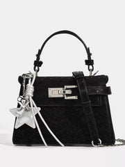 Black mini PU leather handbag with a structured silhouette, arched top handle, front buckle strap, silver hardware, and decorative star and key charms.
