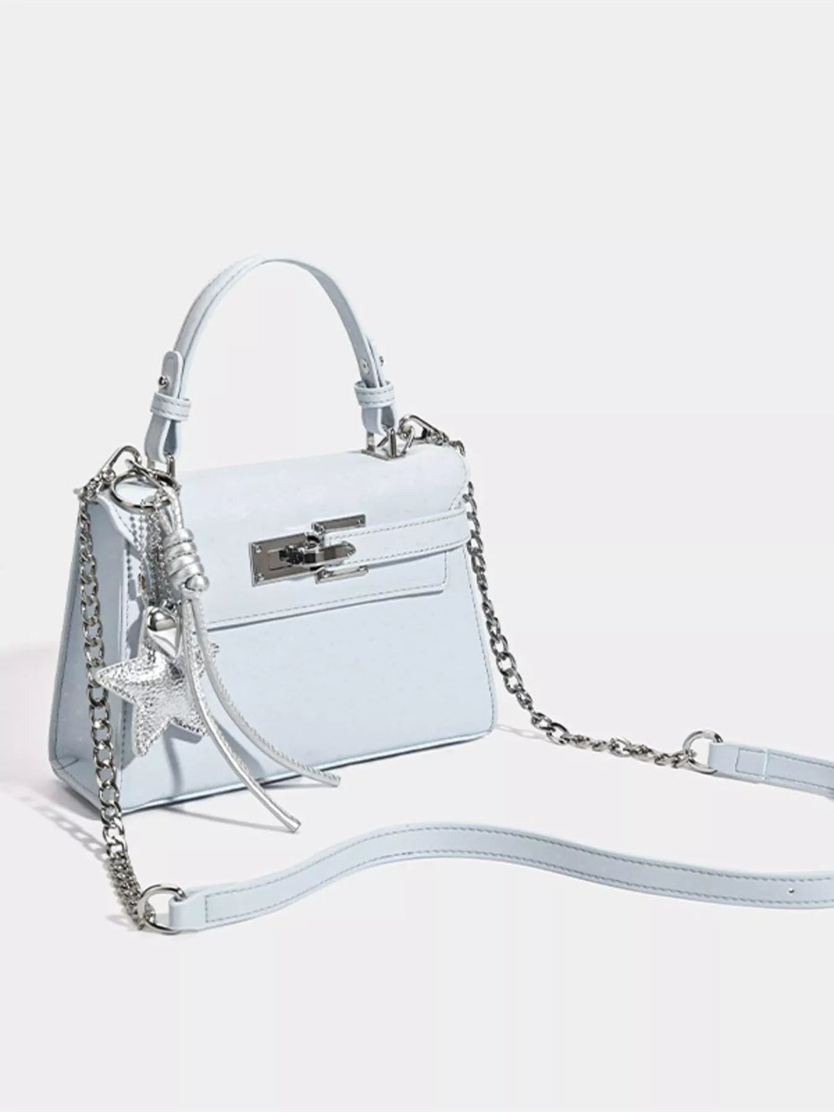 A white mini PU leather handbag with a structured silhouette, rounded top handle, silver buckle closure, chain shoulder strap, and star charm.