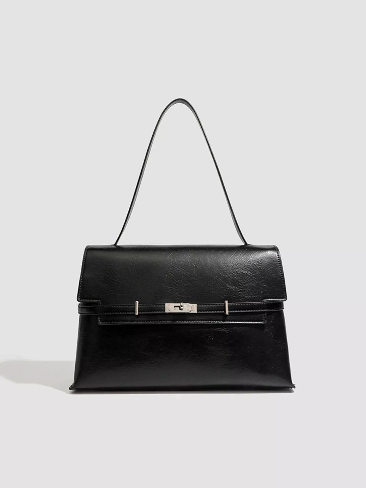 Medium black PU leather shoulder bag with a structured silhouette, smooth flap, slim strap, stitched edges, and a centered metal buckle closure.