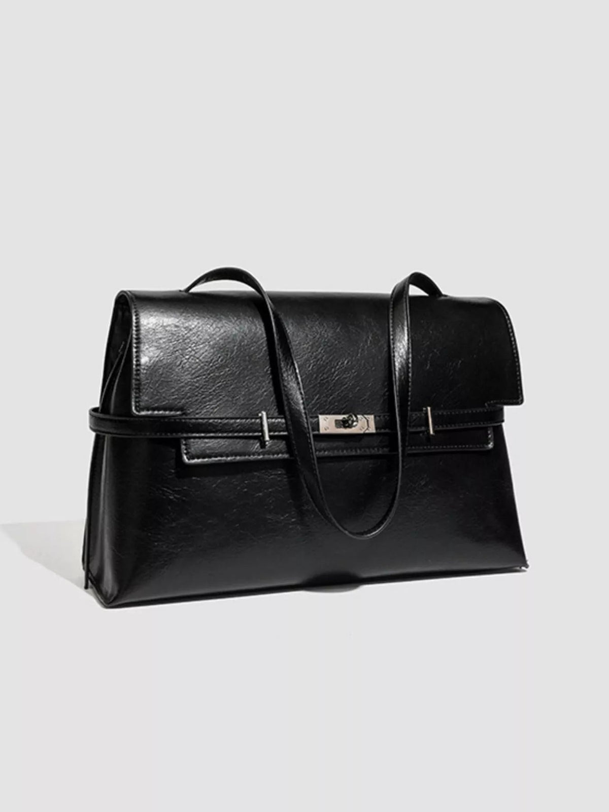 A medium black PU leather shoulder bag with a structured silhouette, flap closure, buckle detail, top handles, and a long shoulder strap.