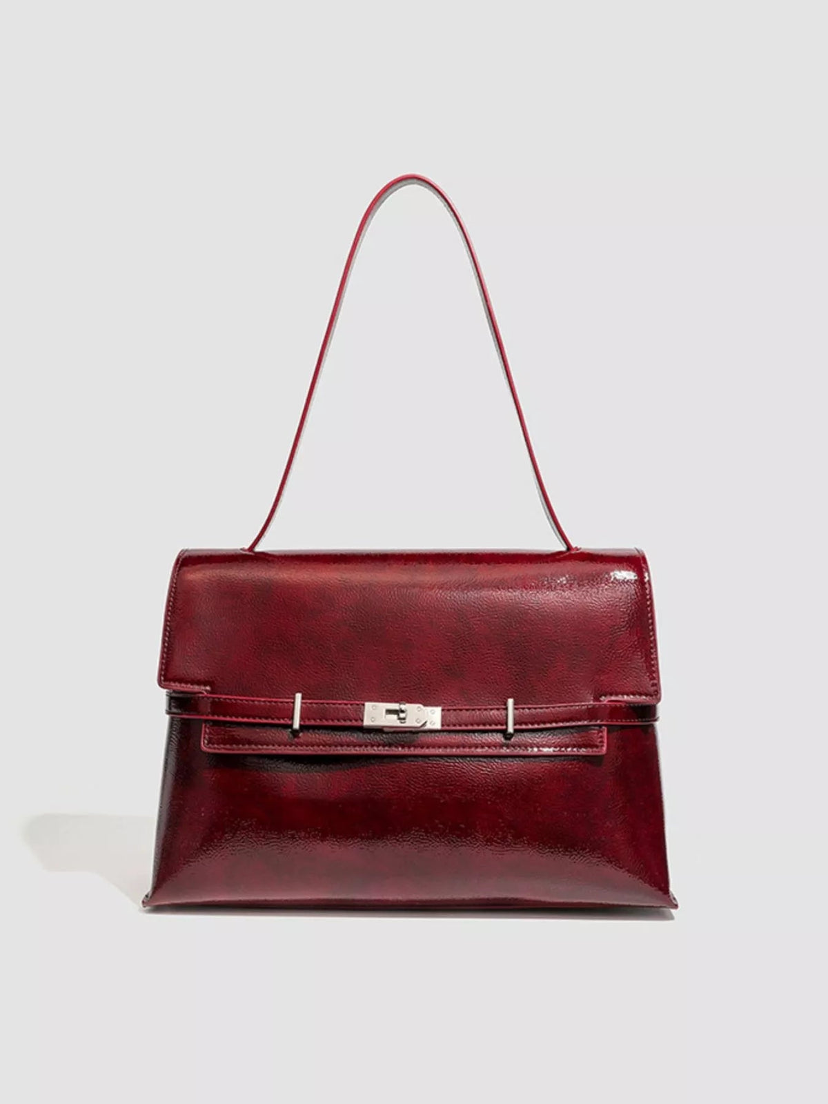 Medium burgundy PU leather shoulder bag with a structured rectangular silhouette, flap closure, central buckle clasp, and long shoulder strap.