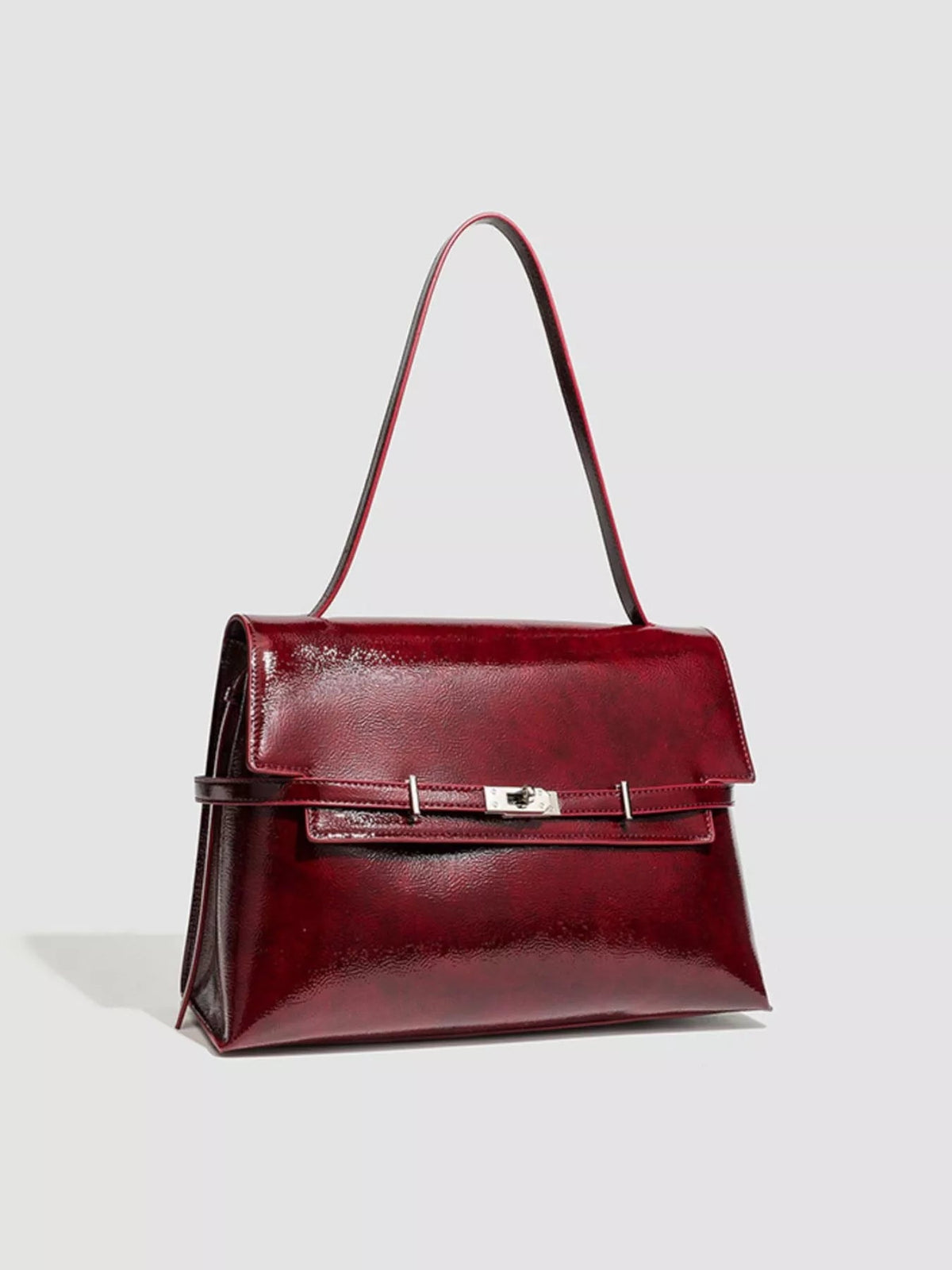 Structured medium burgundy PU leather shoulder bag with a rectangular silhouette, flap closure, long strap, and polished buckle detail.