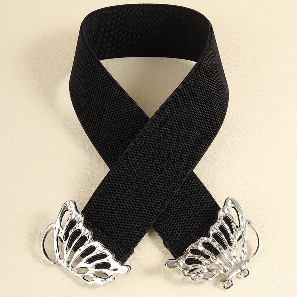 Black elastic belt with a substantial woven band and polished alloy butterfly buckle, shown crossed to highlight its flexible construction and defined 2-inch width.