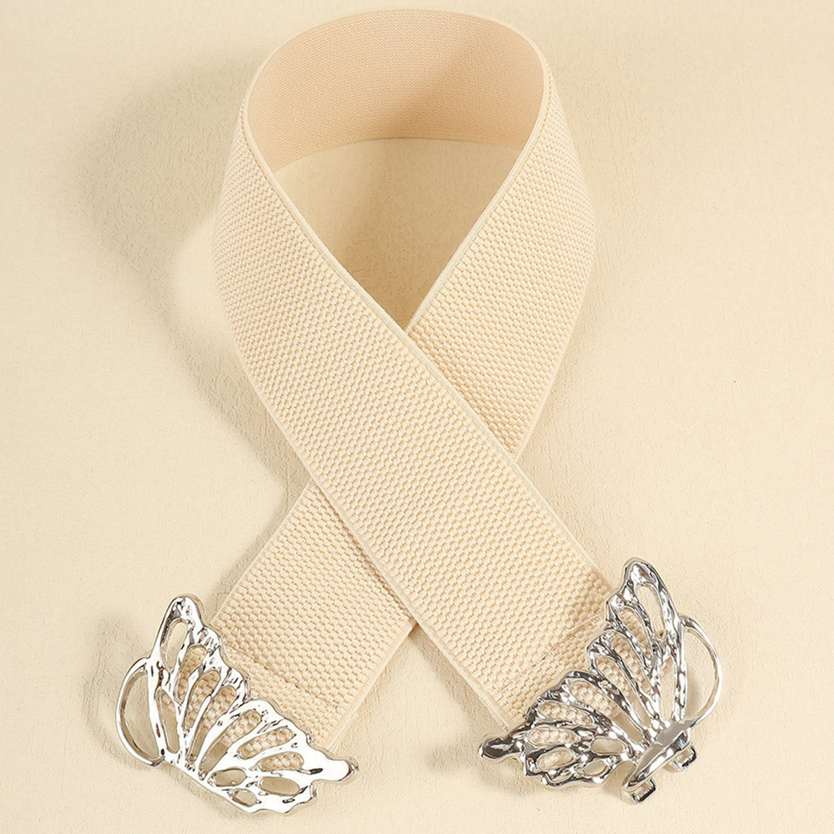 Cream woven elastic belt displayed in an overlapping loop, featuring a wide band and polished silver butterfly alloy buckle with openwork wing details.