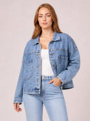 A model poses in a light blue button-down denim jacket with drop shoulders, long sleeves, a relaxed silhouette, and two front patch pockets.