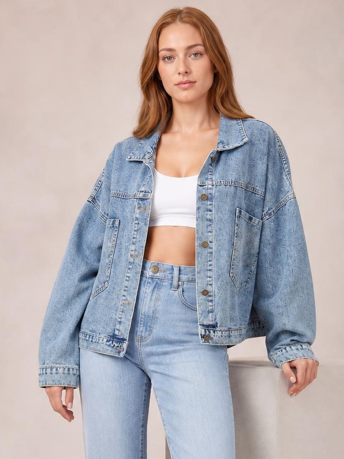 A model wears a light blue button-down denim jacket with drop shoulders, oversized sleeves, front buttons, chest seams, and roomy patch pockets.