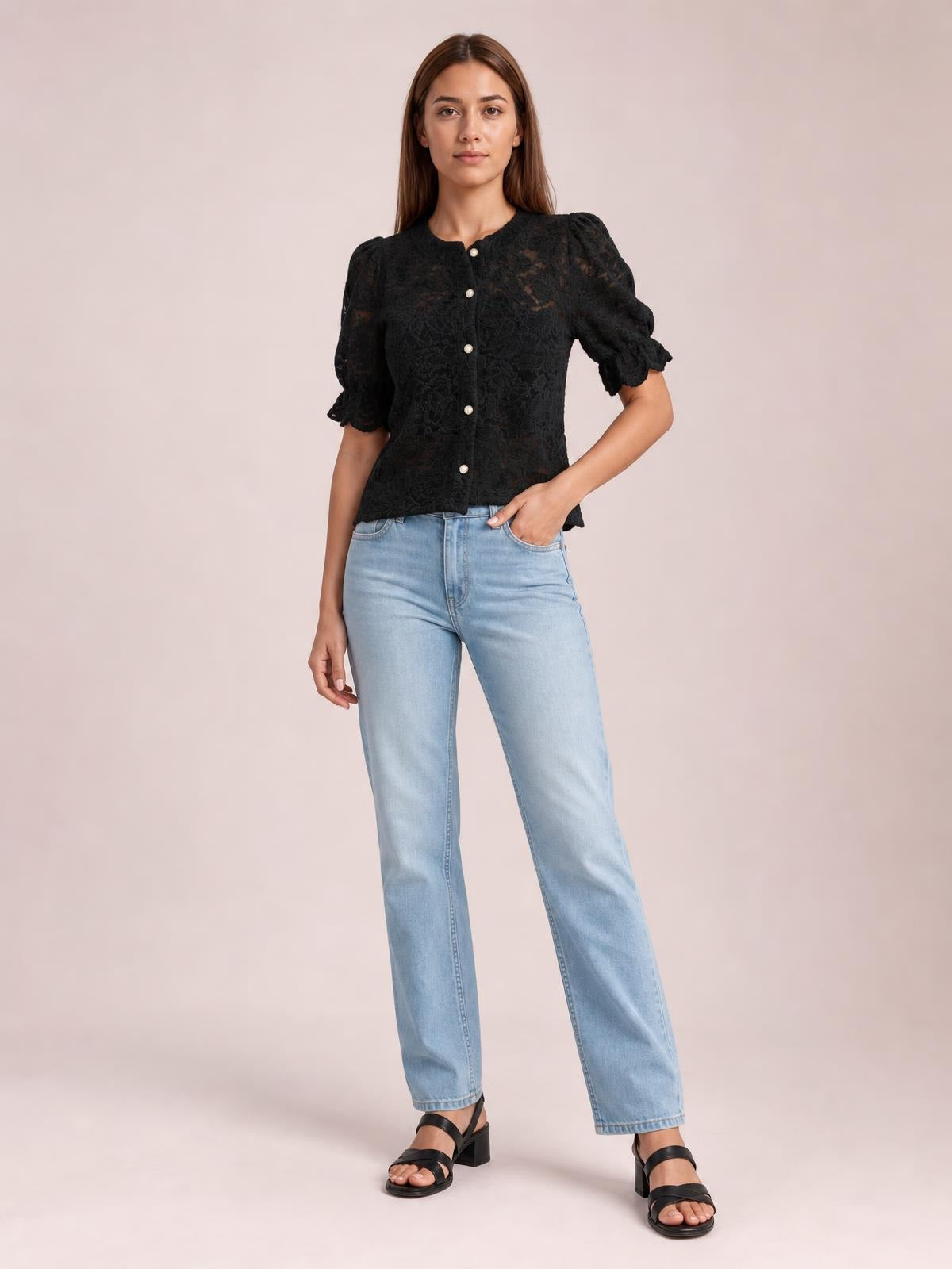 Model poses in a black sheer lace button-down shirt with half sleeves, puffed shoulders, ruffled cuffs, and a fitted cropped silhouette.
