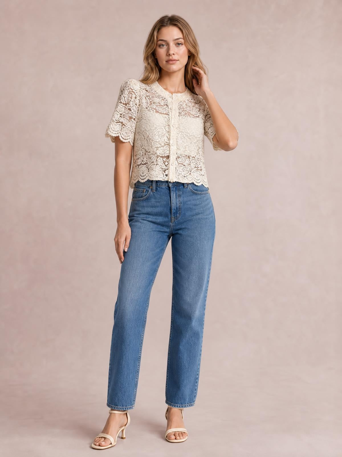 Model wearing a cream sheer lace shirt with button-down front, scalloped hem, and short sleeves in a relaxed cropped silhouette.