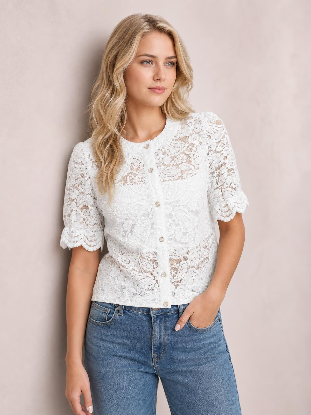 Model poses in a white sheer lace shirt with a button-down front, rounded neckline, half sleeves, scalloped cuffs, and a cropped silhouette.