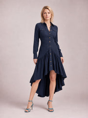 Model wearing a navy button-down shirt dress with long sleeves, chest pockets, a fitted waist, and a ruffled high-low hem, posing with one leg forward.