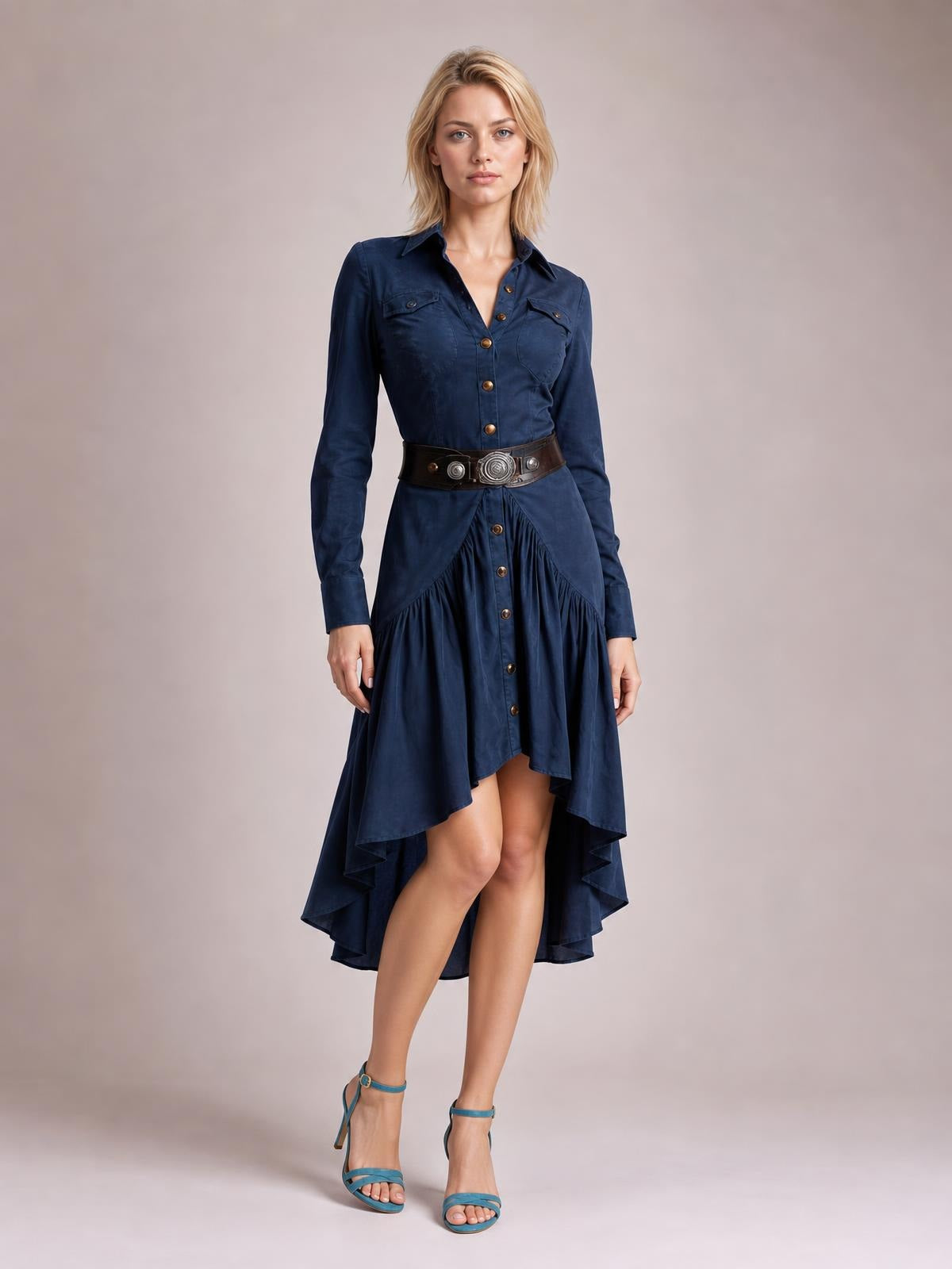Model stands with crossed legs in a navy button-down shirt dress featuring a collared long-sleeve bodice, chest pockets, ruffled panels, and a high-low hem.