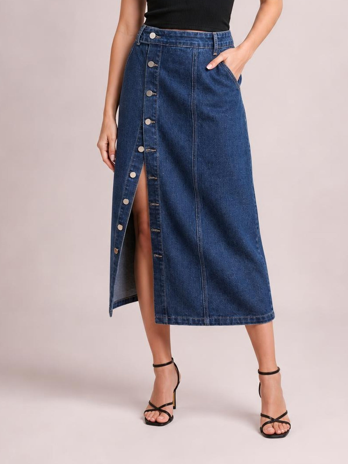 Model wears a dark blue button-down midi denim skirt with a straight silhouette, front seam, functional pockets, and a visible front slit.