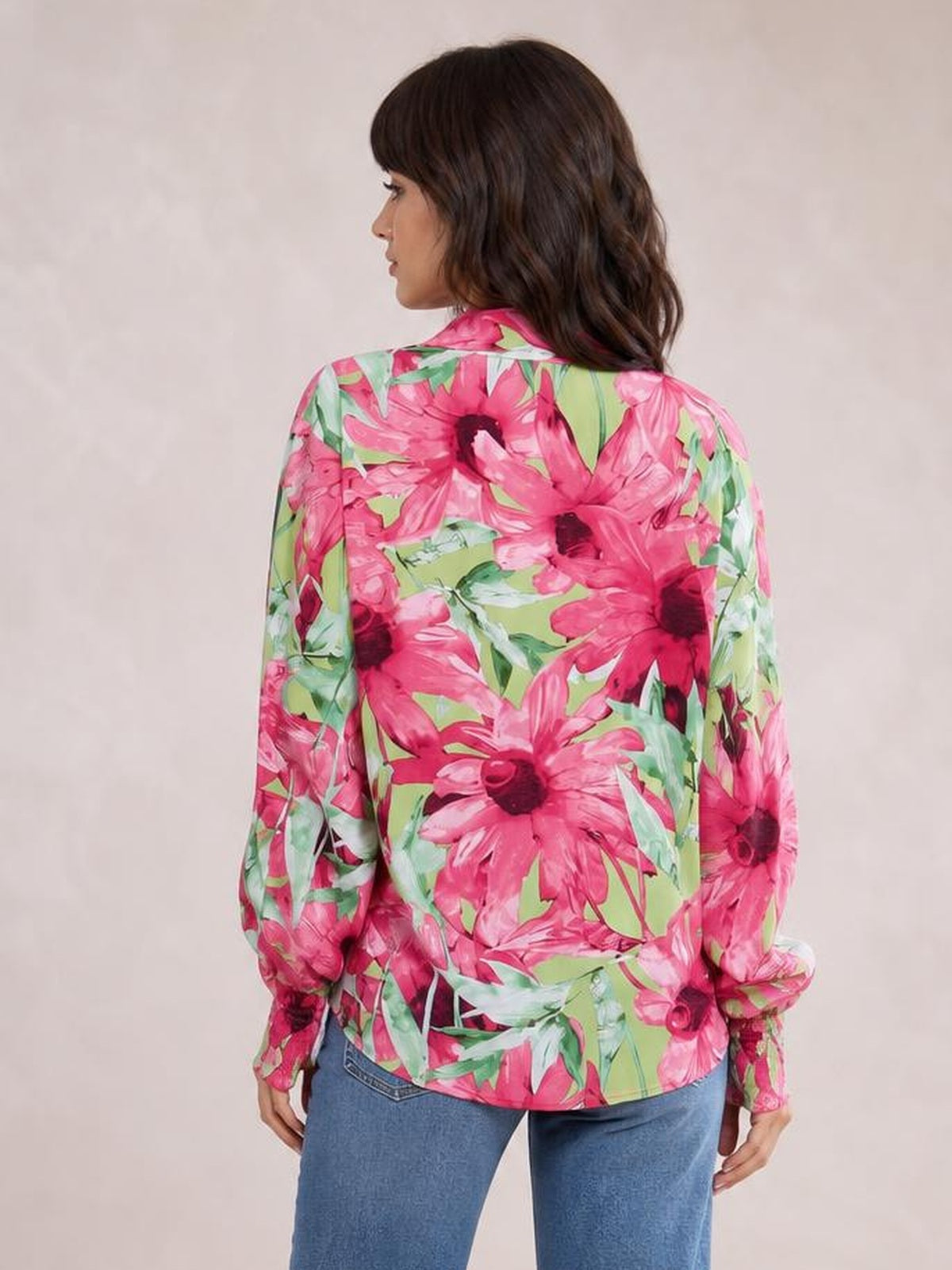 Model shown from the back in a pink and green floral printed button-down long sleeve shirt with a relaxed silhouette and curved hem.