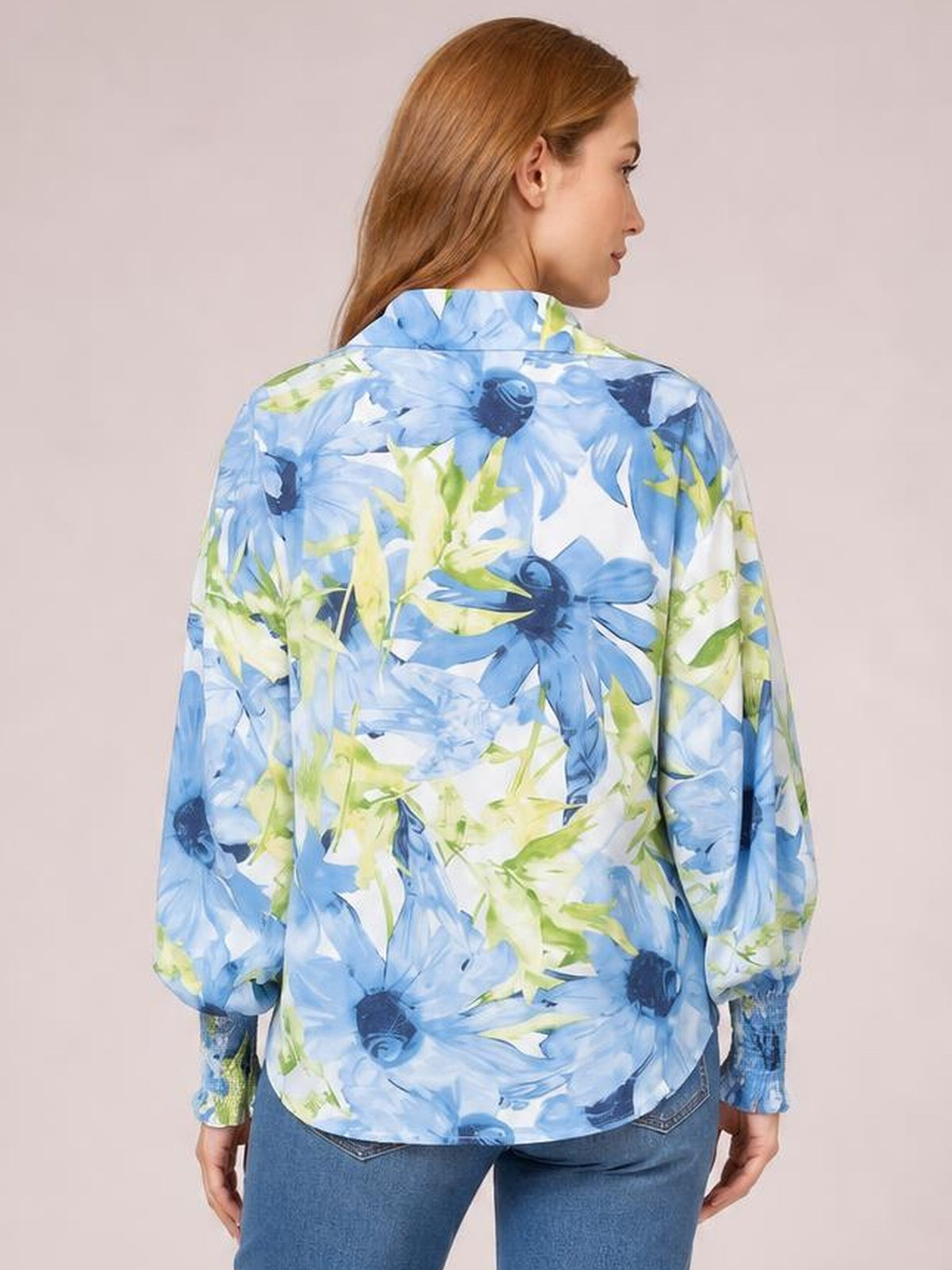Model shown from the back wearing a relaxed button-down printed long sleeve shirt with a blue and green floral pattern and curved hem.
