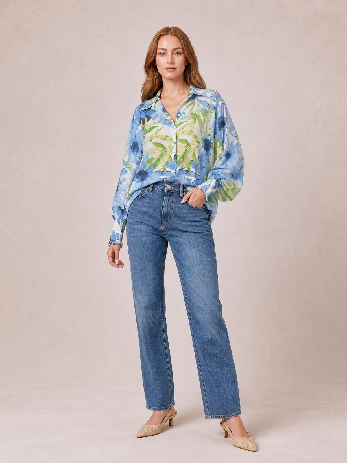 Model poses in a blue and green floral printed button-down shirt with a collared neckline, long sleeves, button front, and relaxed silhouette.
