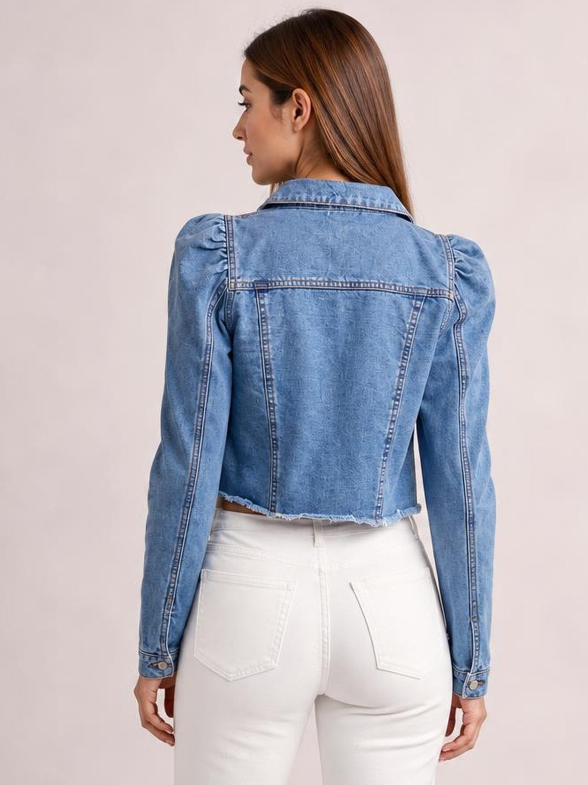 A model wears a light blue cropped denim jacket with a pointed collar, long sleeves, structured back seams, and a distressed raw hem.