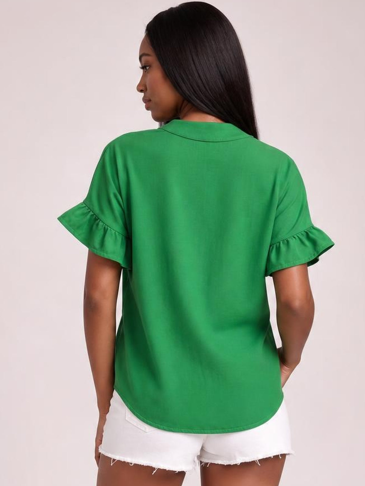 Model shown from the back in a bright green button-down shirt with short ruffled sleeves, a loose silhouette, curved hem, and subtle ruching.