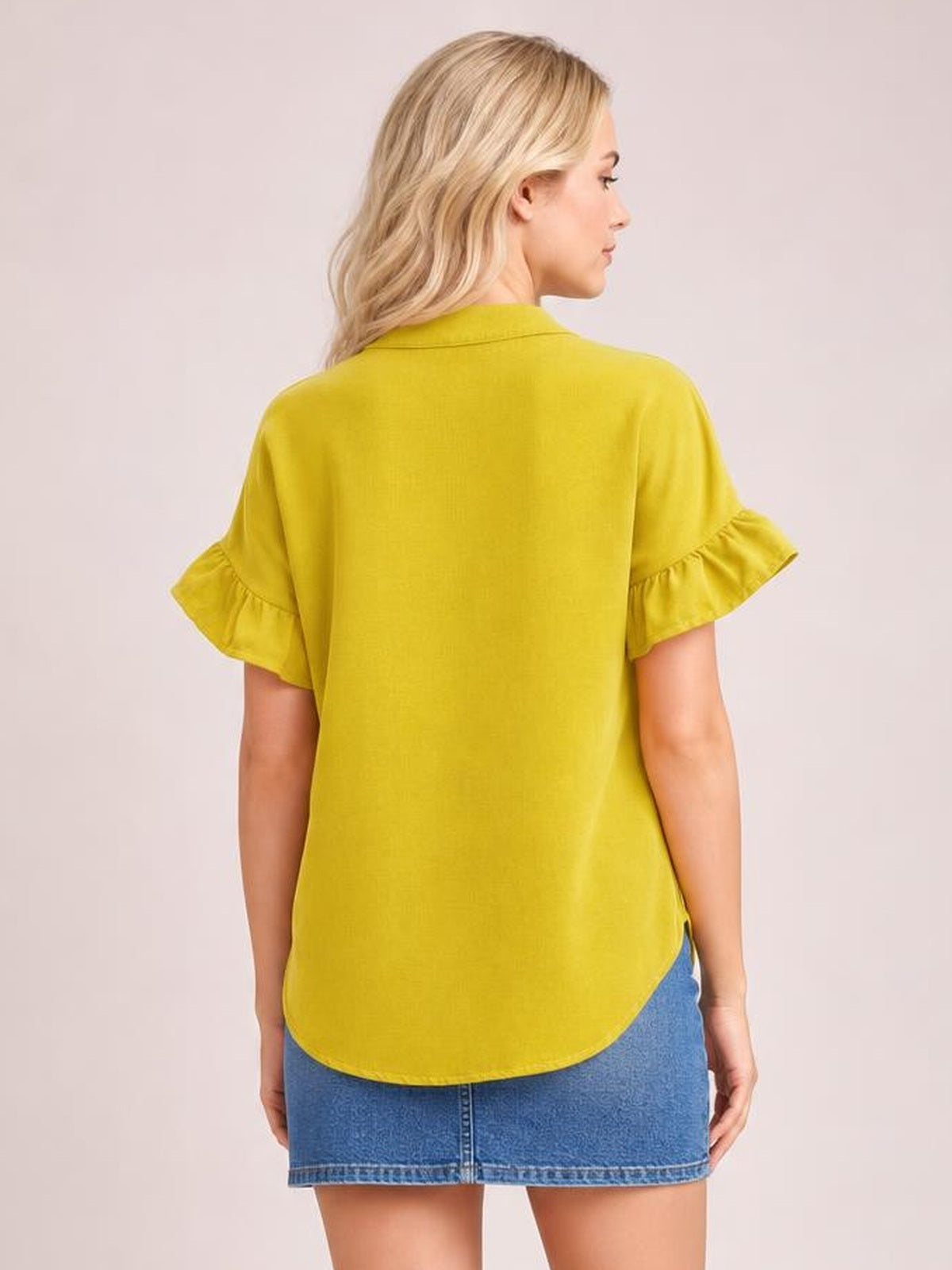 Model shown from behind wearing a bright yellow button-down shirt with a relaxed silhouette, collared neckline, short ruffled sleeves, and a curved hem.