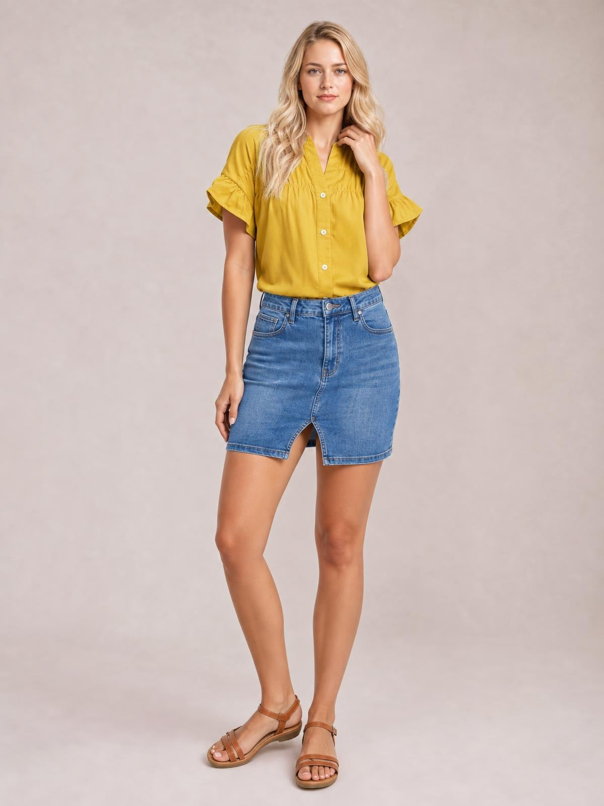 Model stands with one hand touching her hair, wearing a mustard yellow button-down shirt with a relaxed silhouette, ruched front, and ruffled short sleeves.