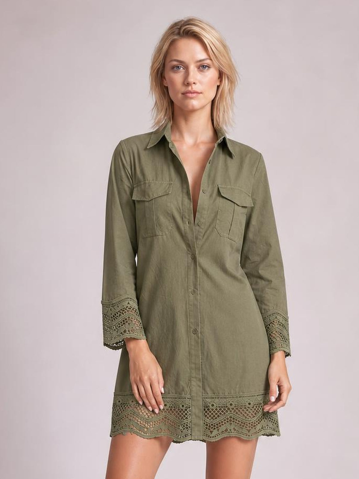 Model stands facing forward in an olive green button-down shirt dress with a relaxed silhouette, chest pockets, and lace-trimmed cuffs and hem.