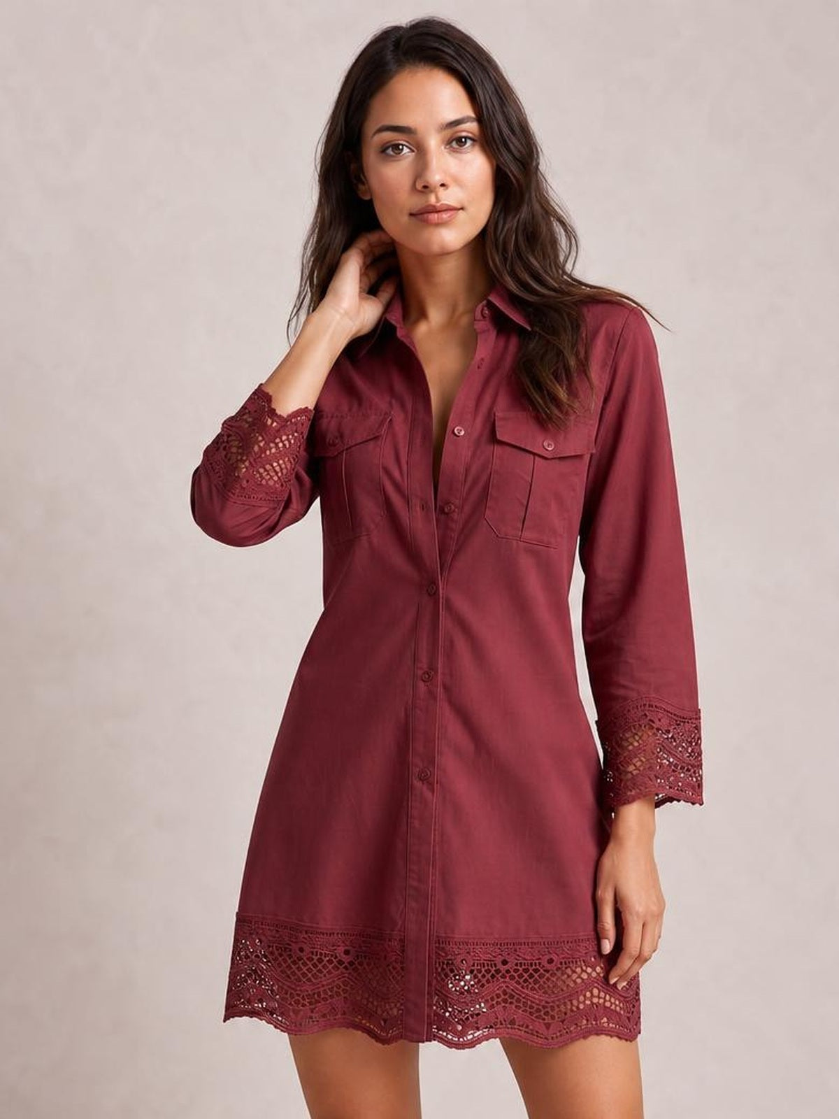 A model poses in a burgundy button-down shirt dress with a collared neckline, long sleeves, front pockets, straight silhouette, and lace trim at the cuffs and hem.