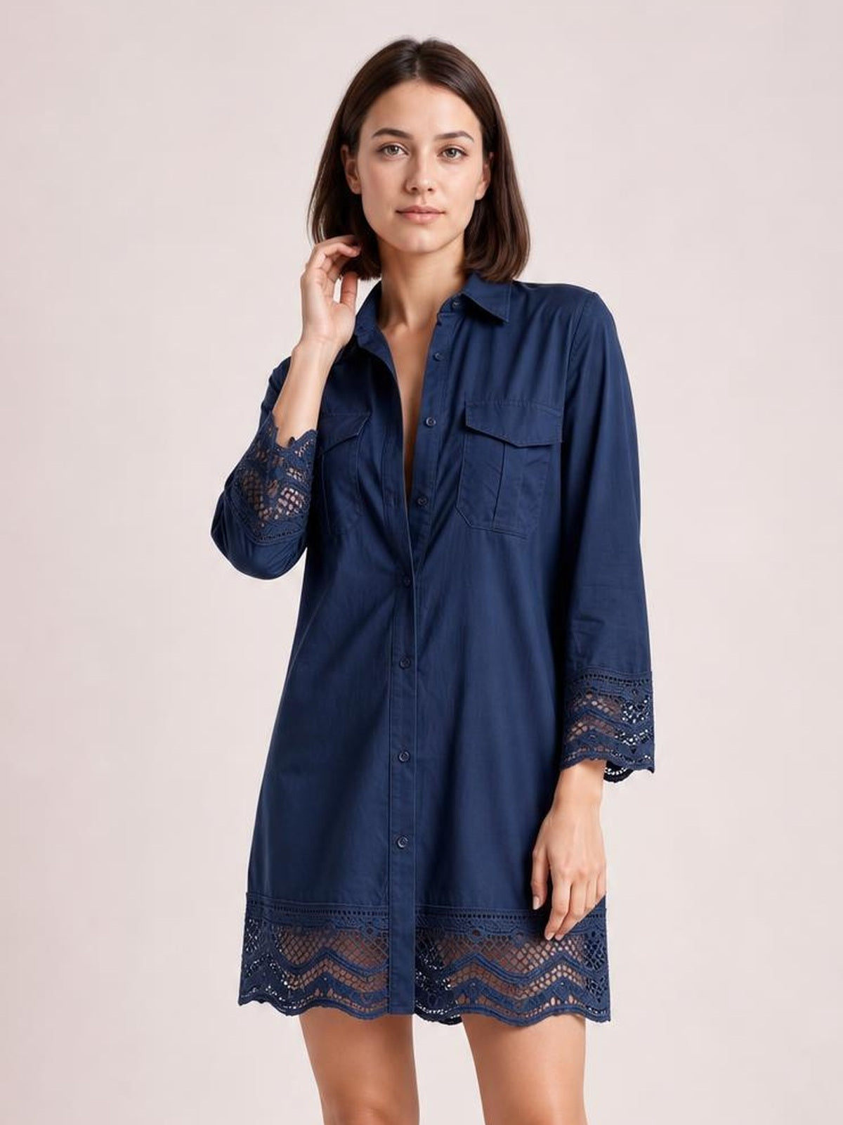 Model poses in a navy button-down shirt dress with a relaxed silhouette, chest pockets, lace-trimmed eyelet cuffs, and a decorative lace hem.
