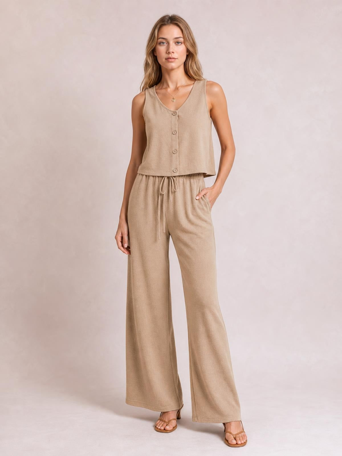 Model poses in a camel button-down vest and drawstring wide-leg pants set, featuring a sleeveless V-neck top and relaxed flowing silhouette.