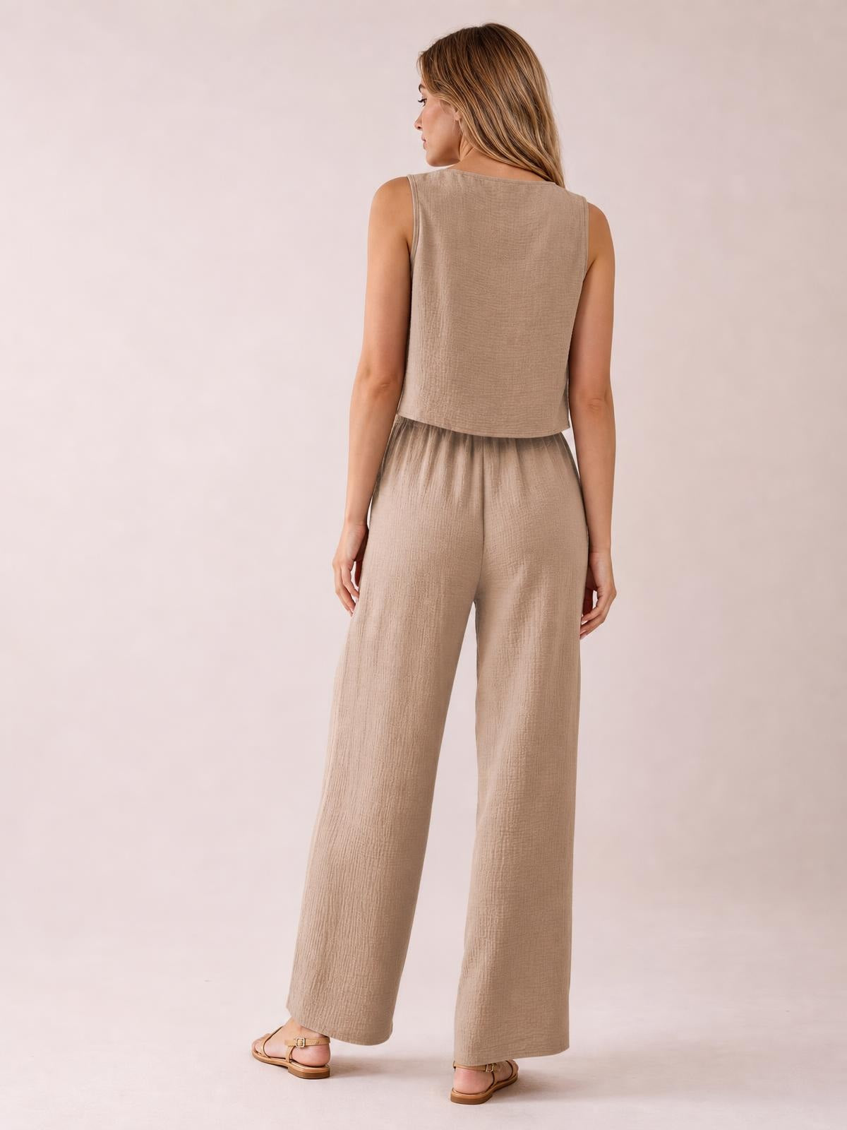 A model stands turned away in a camel sleeveless vest and drawstring wide-leg pants set, showing the cropped vest silhouette and relaxed flowing legs.