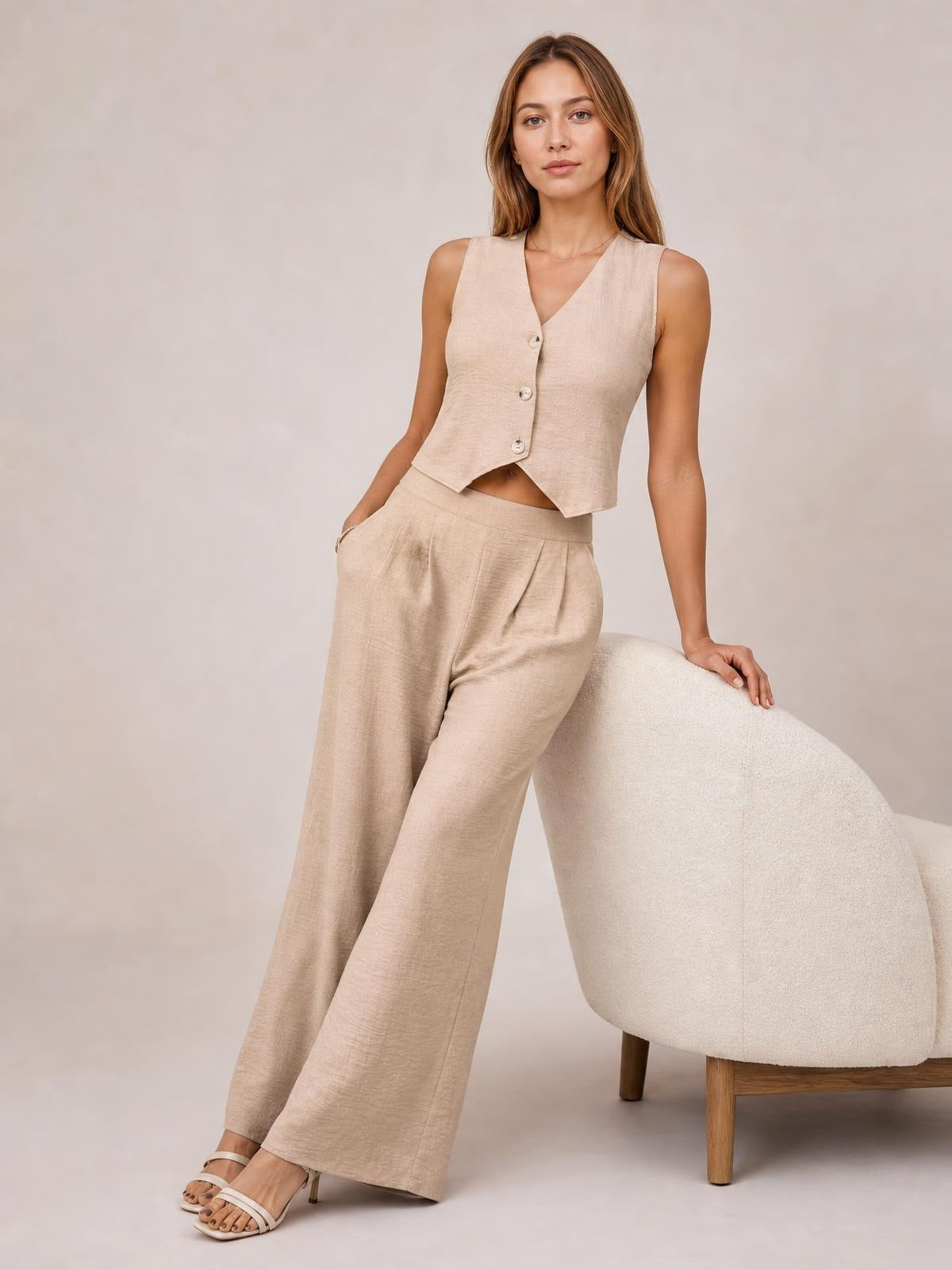 Model poses in a beige button-down vest and matching high-waisted wide-leg pants, featuring a tailored silhouette, front buttons, and pockets.