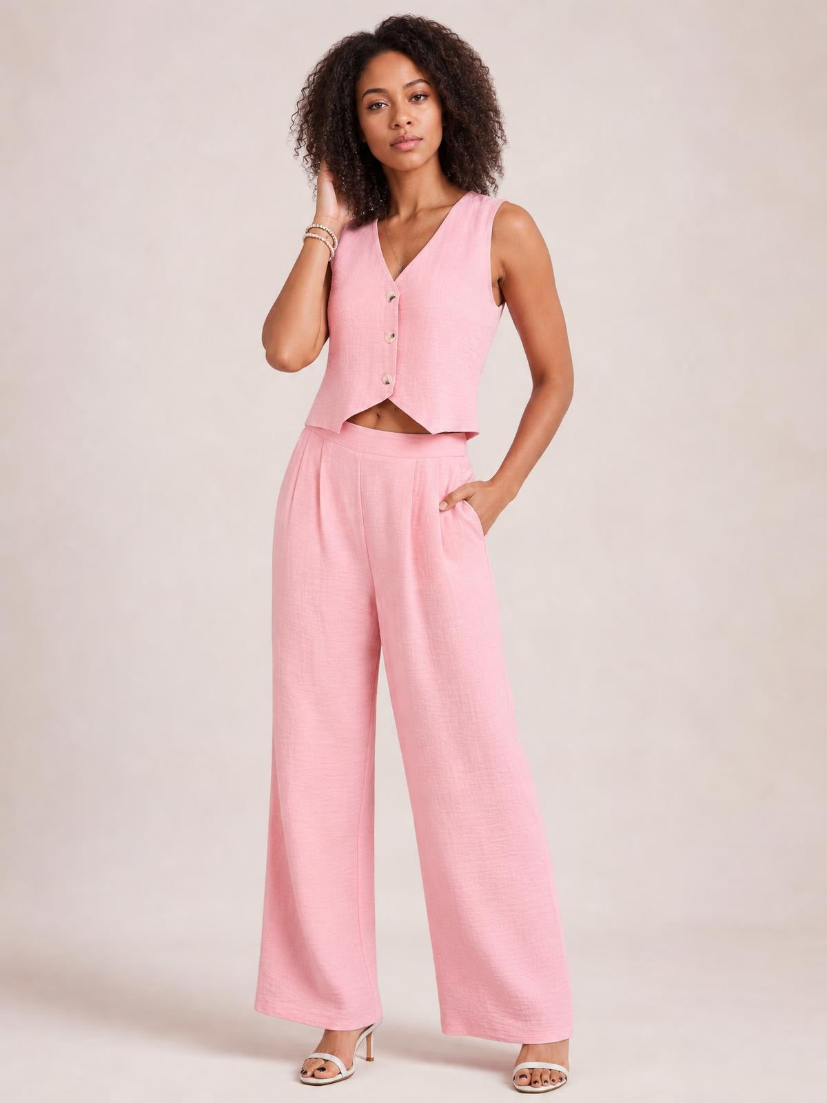 A model poses in a pink button-down vest and matching wide-leg pants set, showing the cropped silhouette, front buttons, fluid legs, and practical pockets.