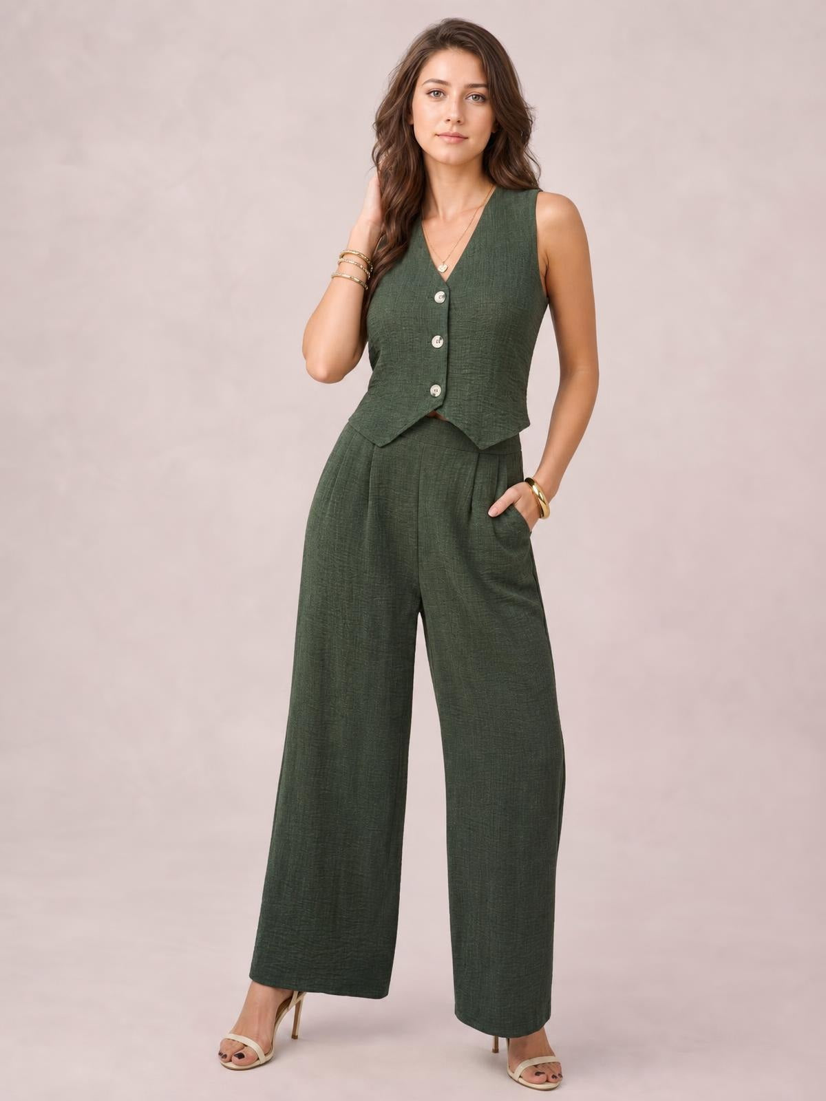 A model poses in a dark green button-down vest and matching wide-leg pants set, featuring a sleeveless tailored silhouette and practical side pockets.
