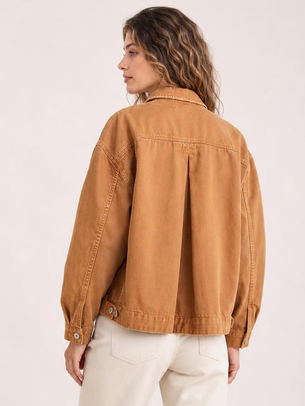 Model shown from the back in a camel button-up denim jacket with drop shoulders, long sleeves, back pleat, and visible seam detailing.