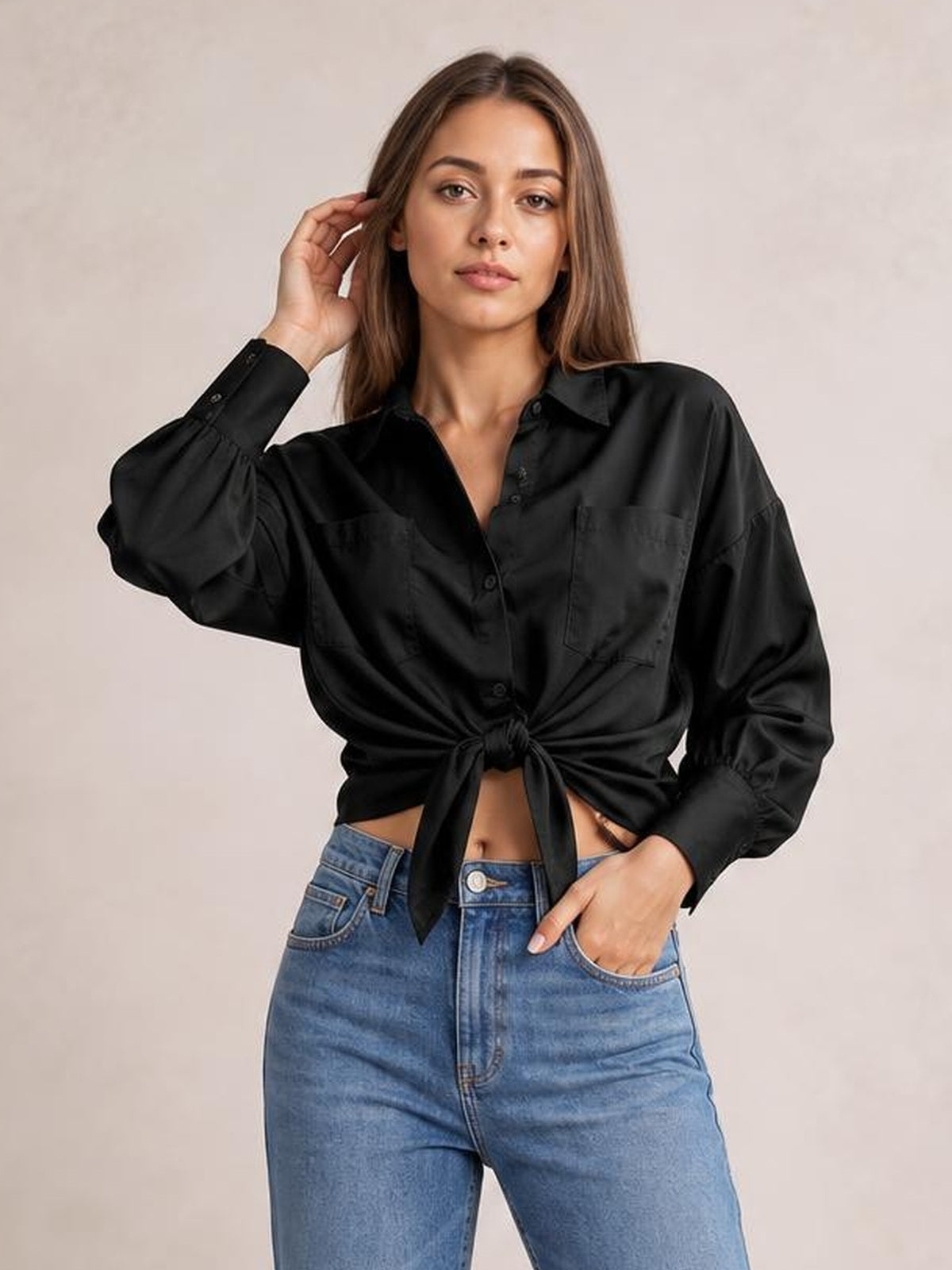 A model poses in a black button-up shirt with dropped shoulders, lantern sleeves, chest pockets, and a front tie creating a cropped silhouette.