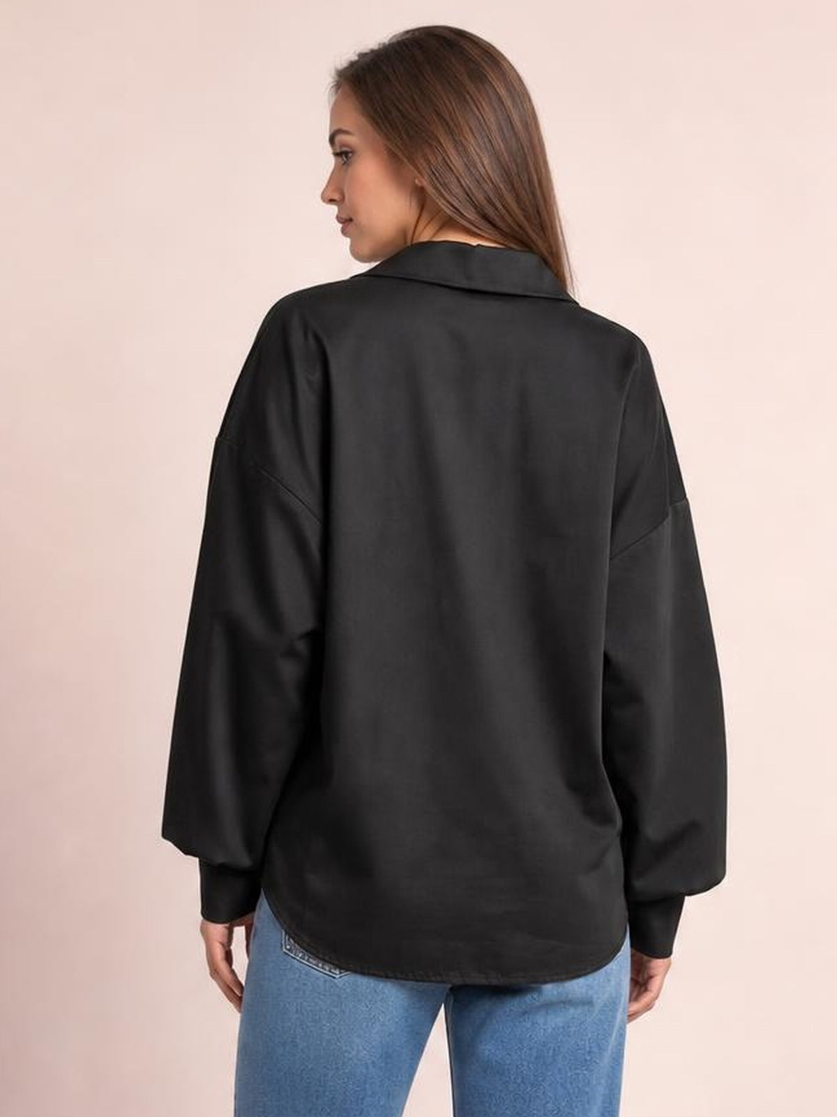 Model shown from the back wearing a black button-up shirt with a dropped shoulder, oversized lantern sleeves, collared neckline, and relaxed curved hem.