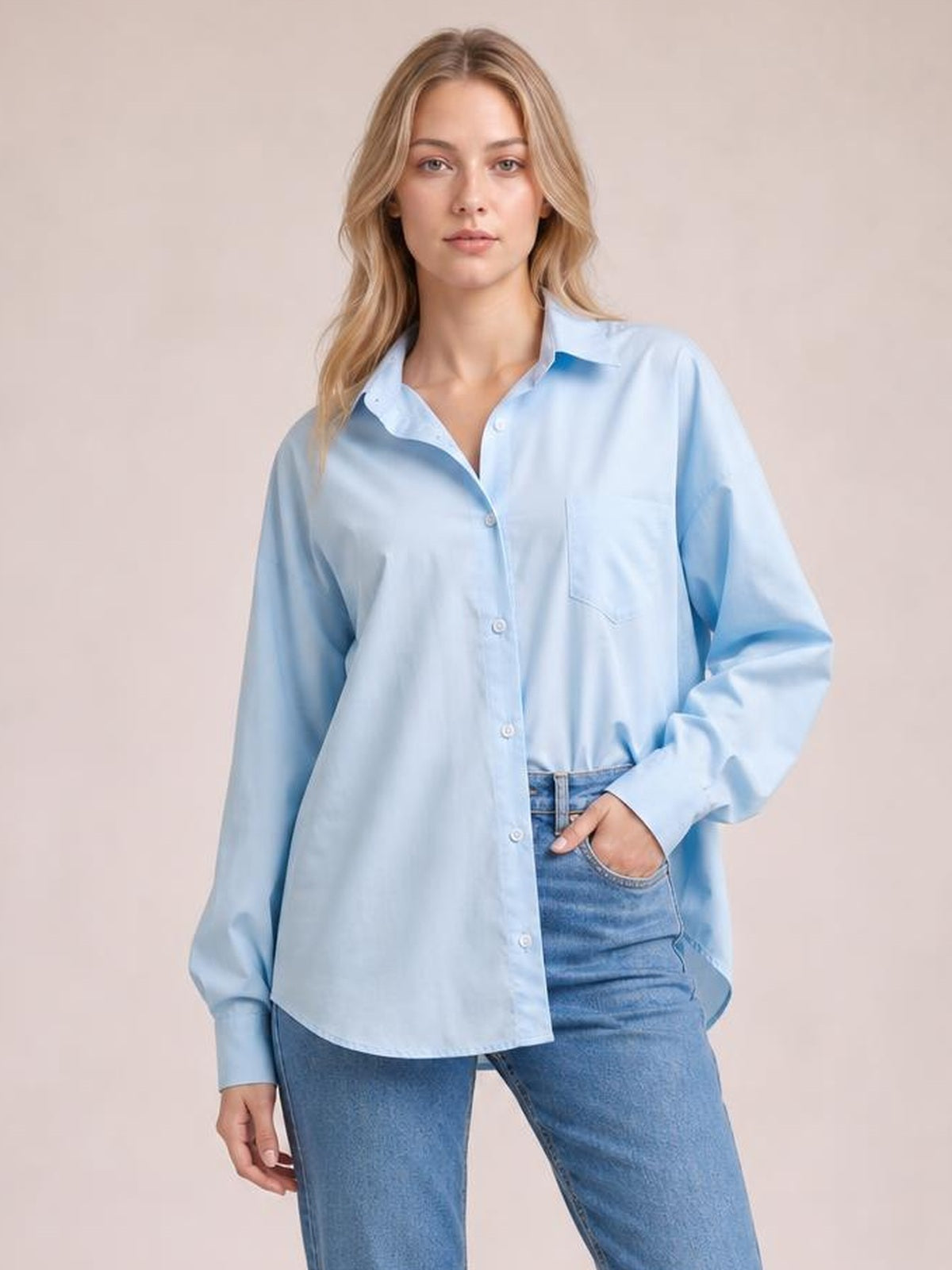 Model wears a light blue button-up shirt with dropped shoulders, relaxed lantern sleeves, a curved hem, and a practical chest pocket.