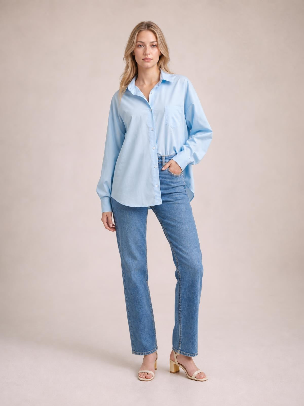 Model wearing a light blue button-up shirt with a relaxed dropped-shoulder silhouette, chest pocket, curved hem, and voluminous lantern sleeves.