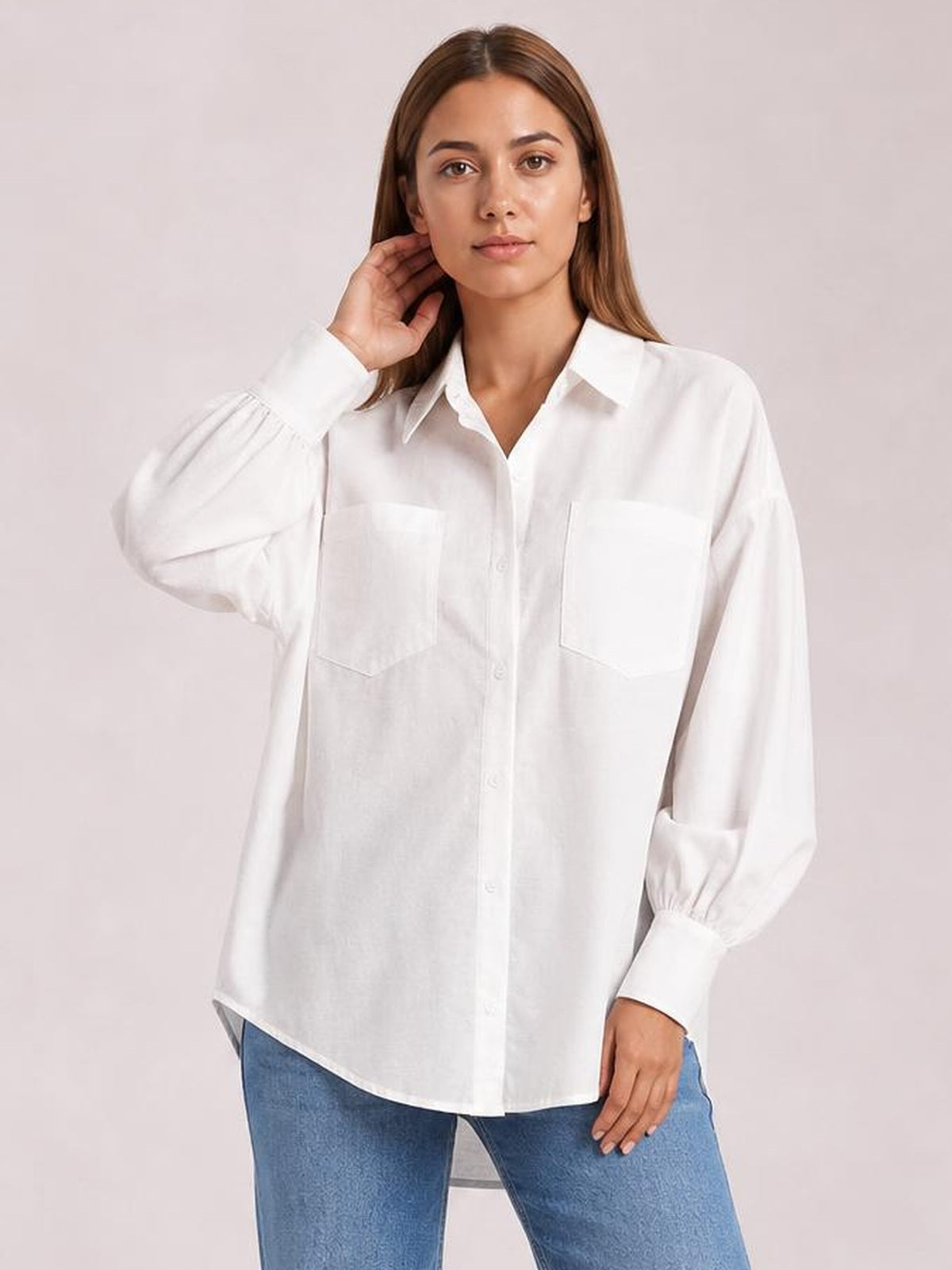 Model wears a white button-up shirt with dropped shoulders, voluminous lantern sleeves, two chest pockets, and a relaxed, straight silhouette.