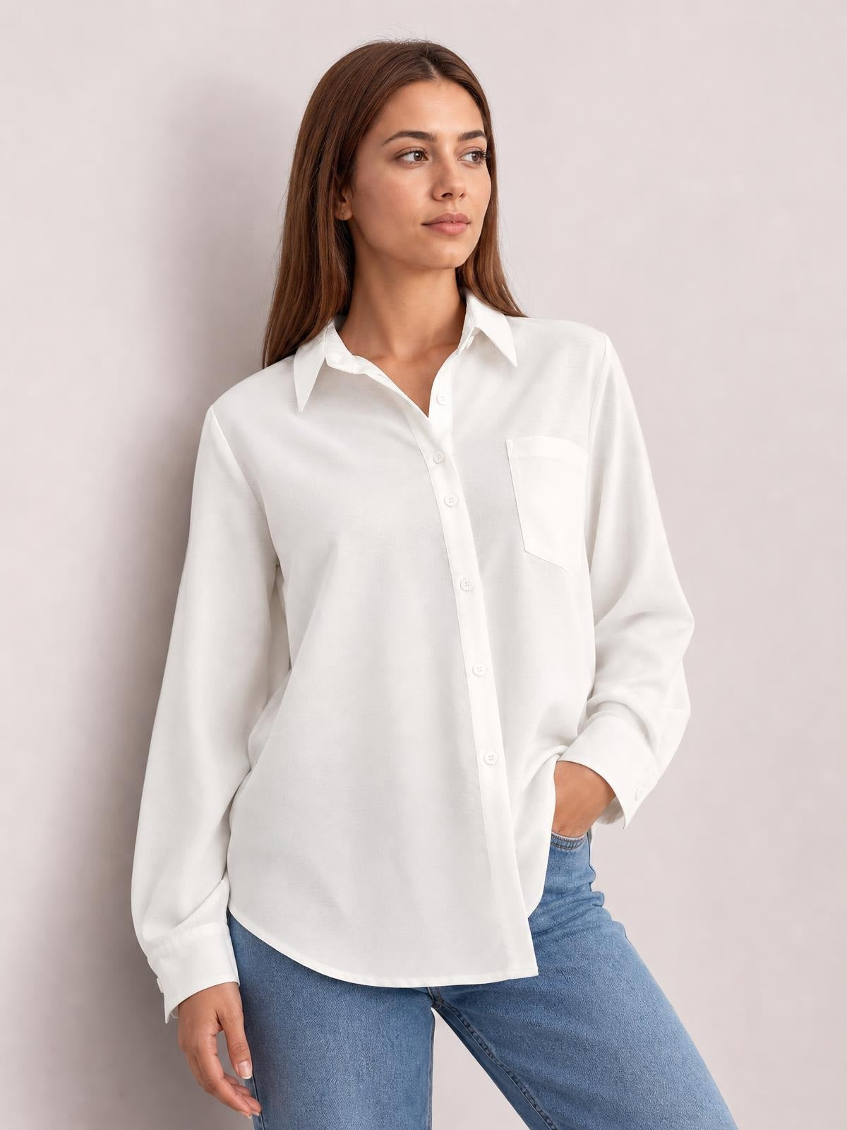 A model poses in a white button-up shirt with dropped shoulders, relaxed silhouette, long lantern sleeves, pointed collar, and a practical chest pocket.